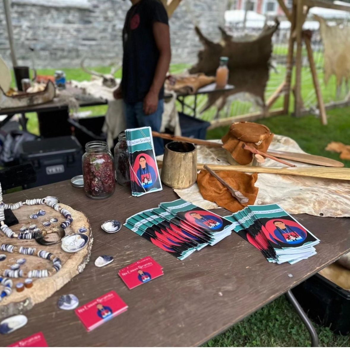 A table displaying craft items and promotional materials; a person stands nearby.