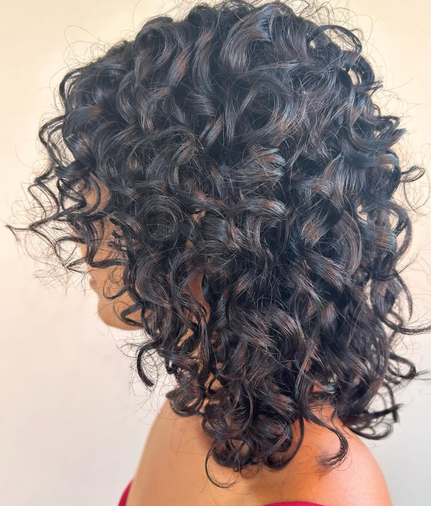 A Woman With Curly Hair — Hairdressers At Work in Cairns City, QLD