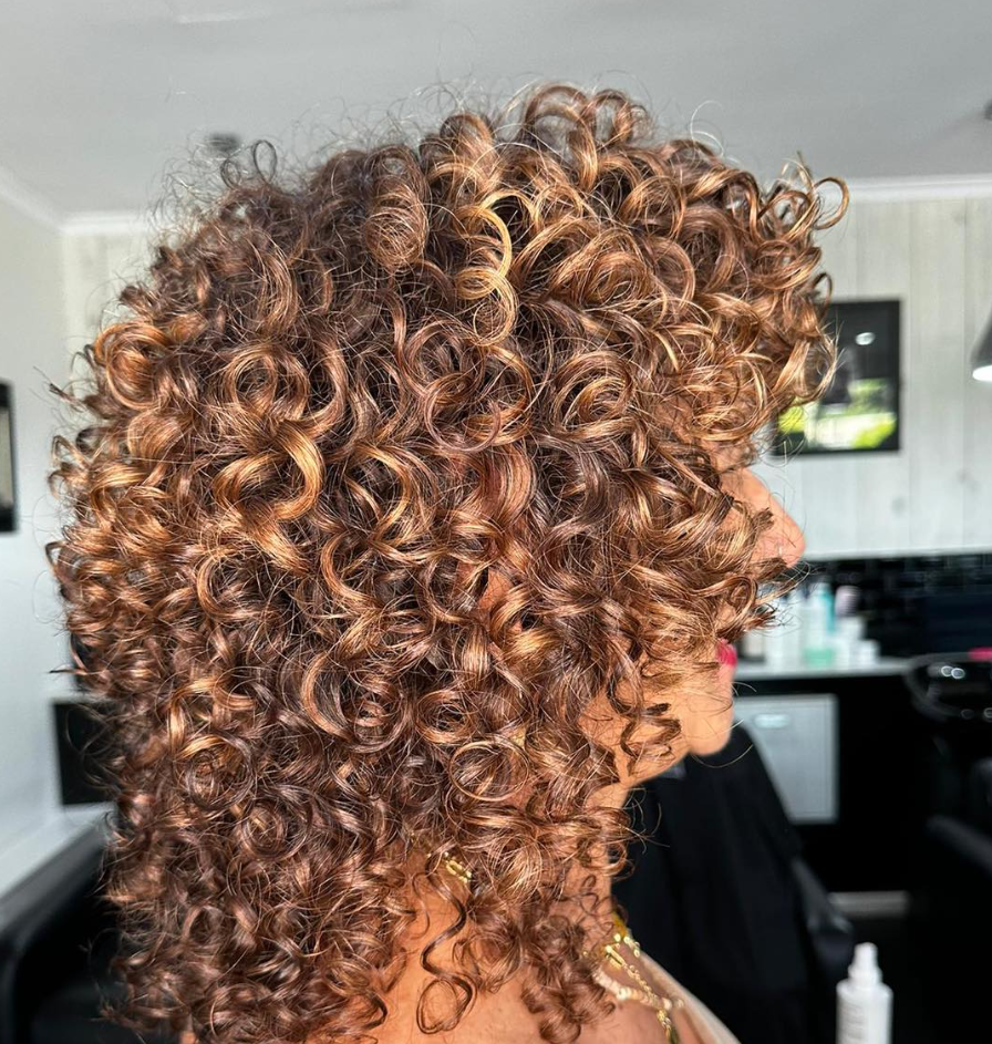 A Woman With Curly Hair — Hairdressers At Work in Cairns City, QLD