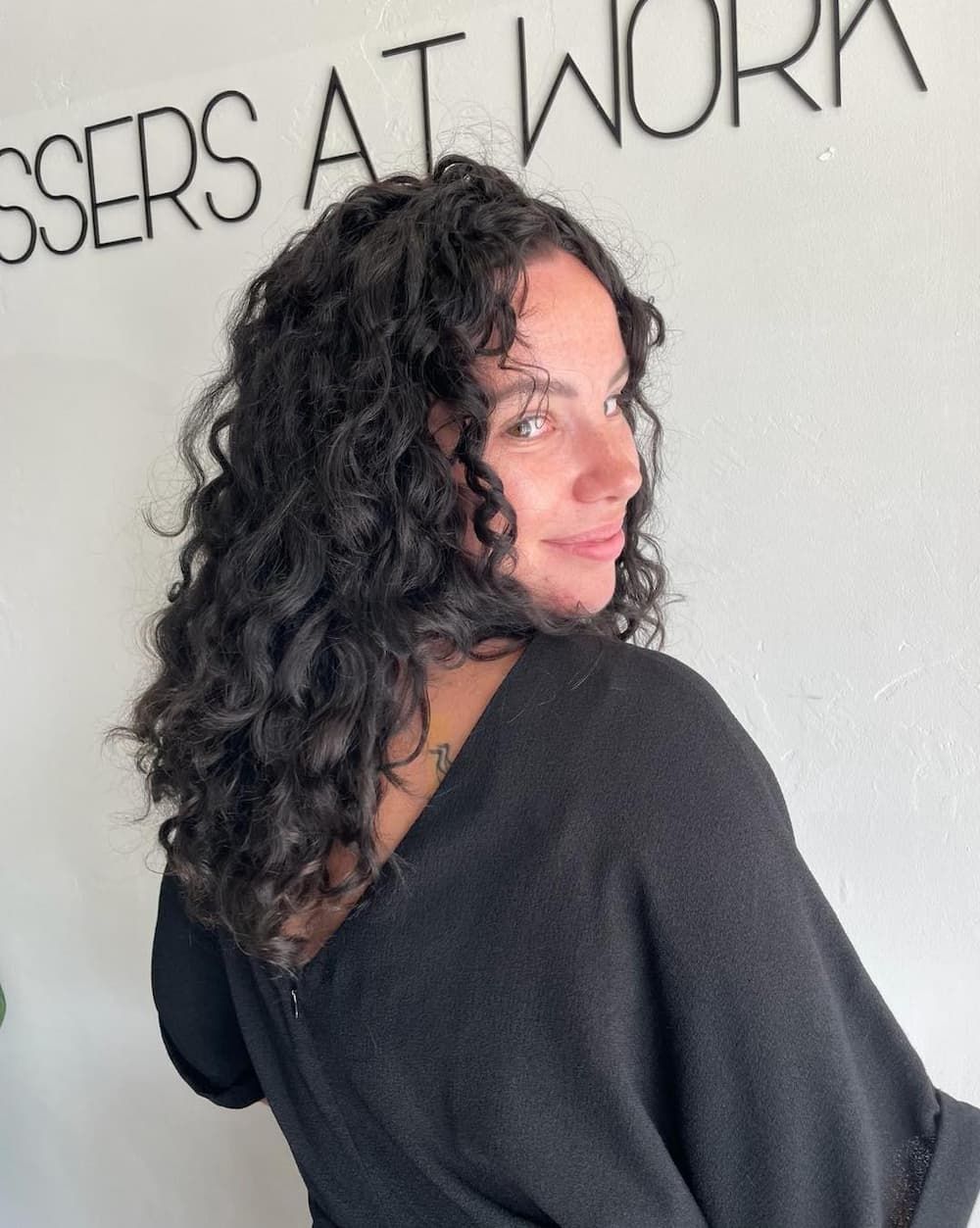 A Woman With Curly Hair is Standing in Front of a Sign That Says Scissors at Work— Hairdresser At Work in Cairns City, QLD