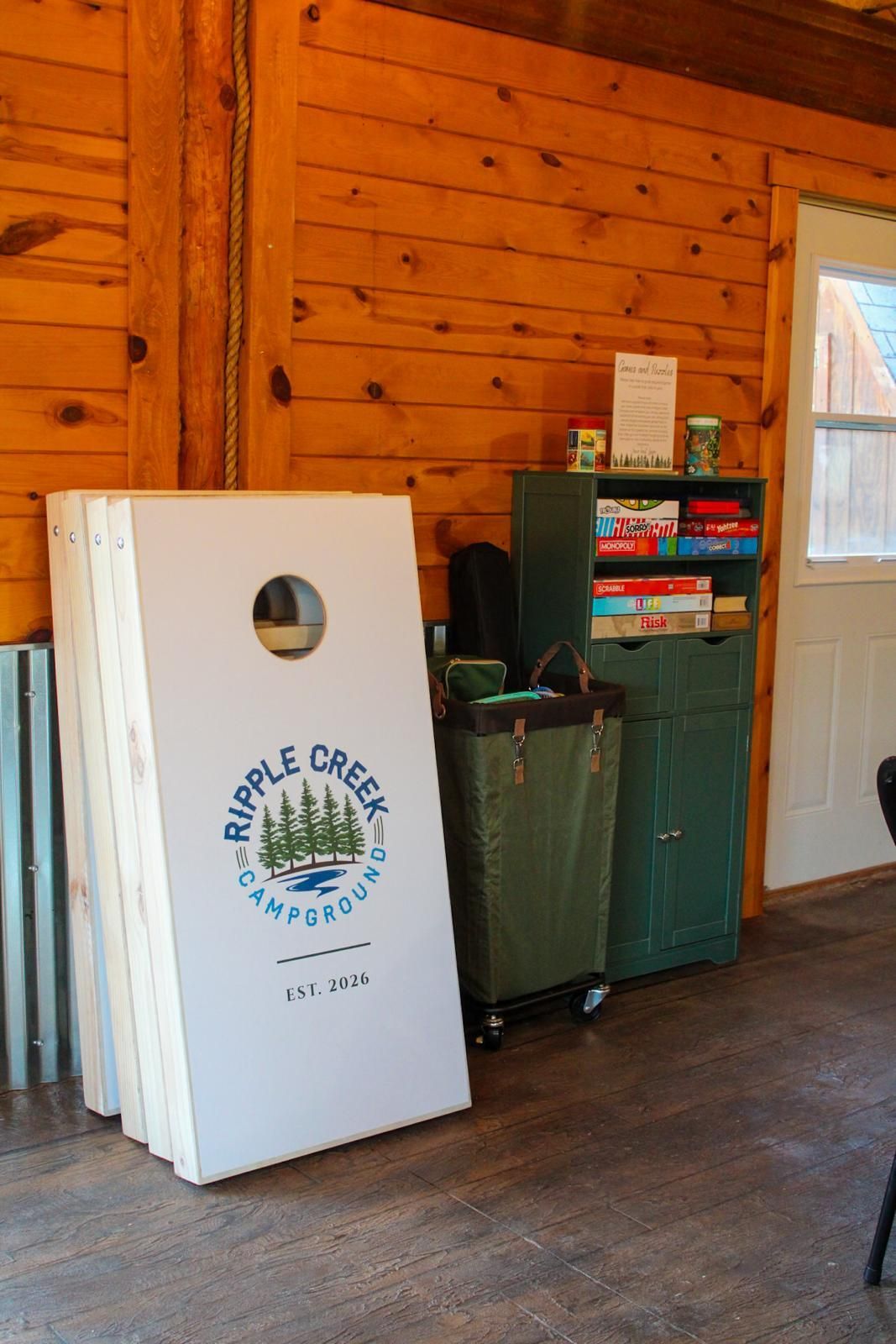 Wood-paneled room with a white recycling bin and green cabinet by a window