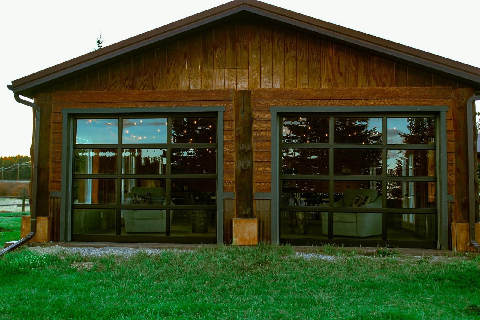 Wooden building with large front windows and a grassy foreground at dusk