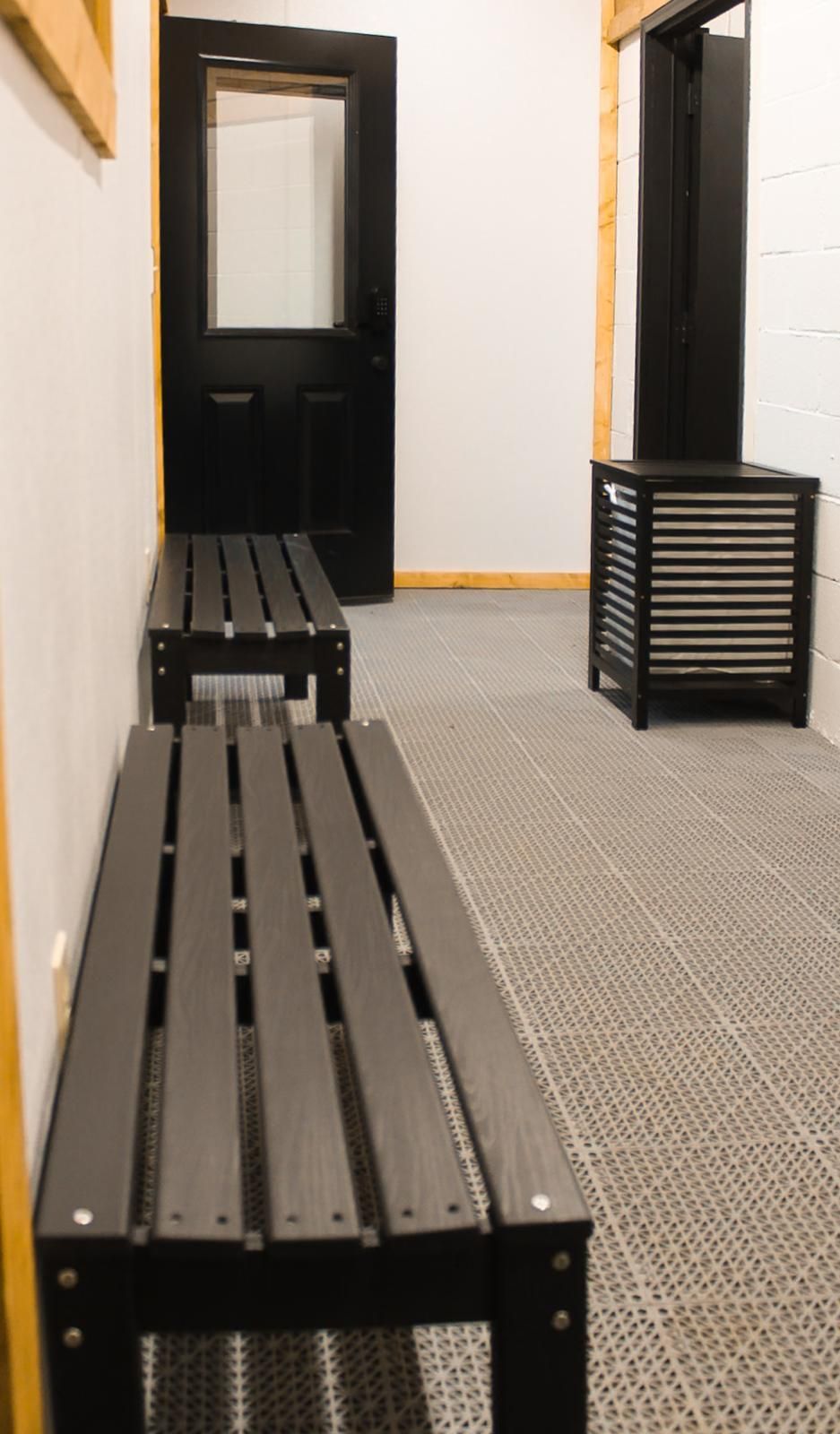 Empty locker room with dark benches and a door at the end