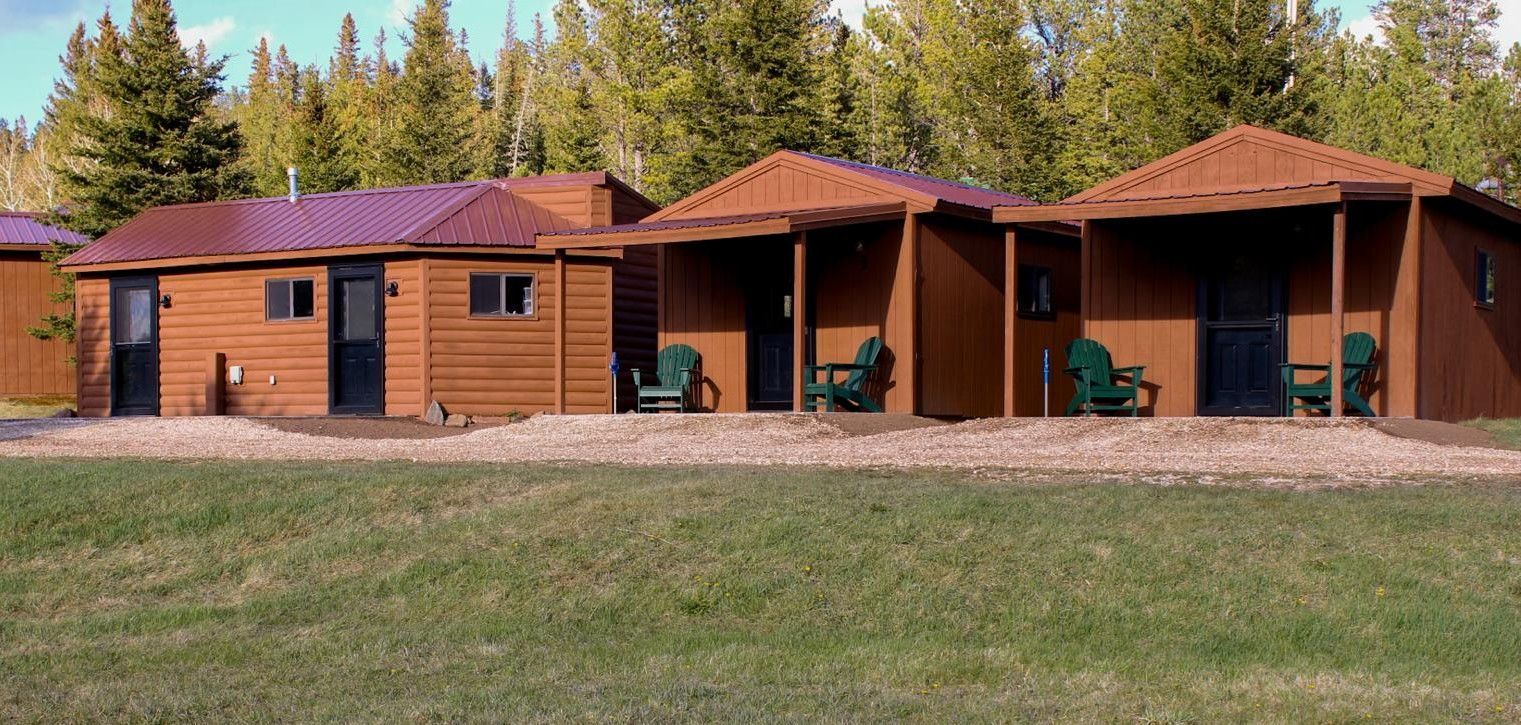 Single-story brick cabins with red roofs and porches in a grassy clearing