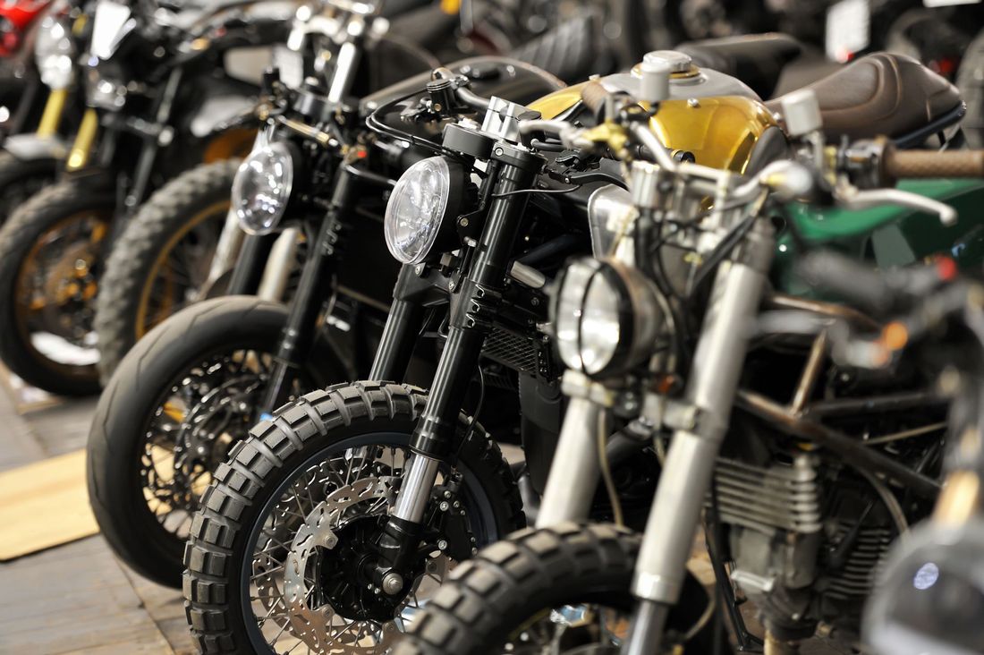 Row of custom motorcycles with knobby tires and round headlights in a workshop