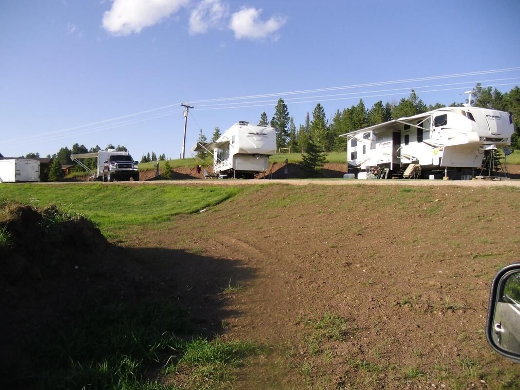 RV trailers parked on a grassy hillside under a clear blue sky