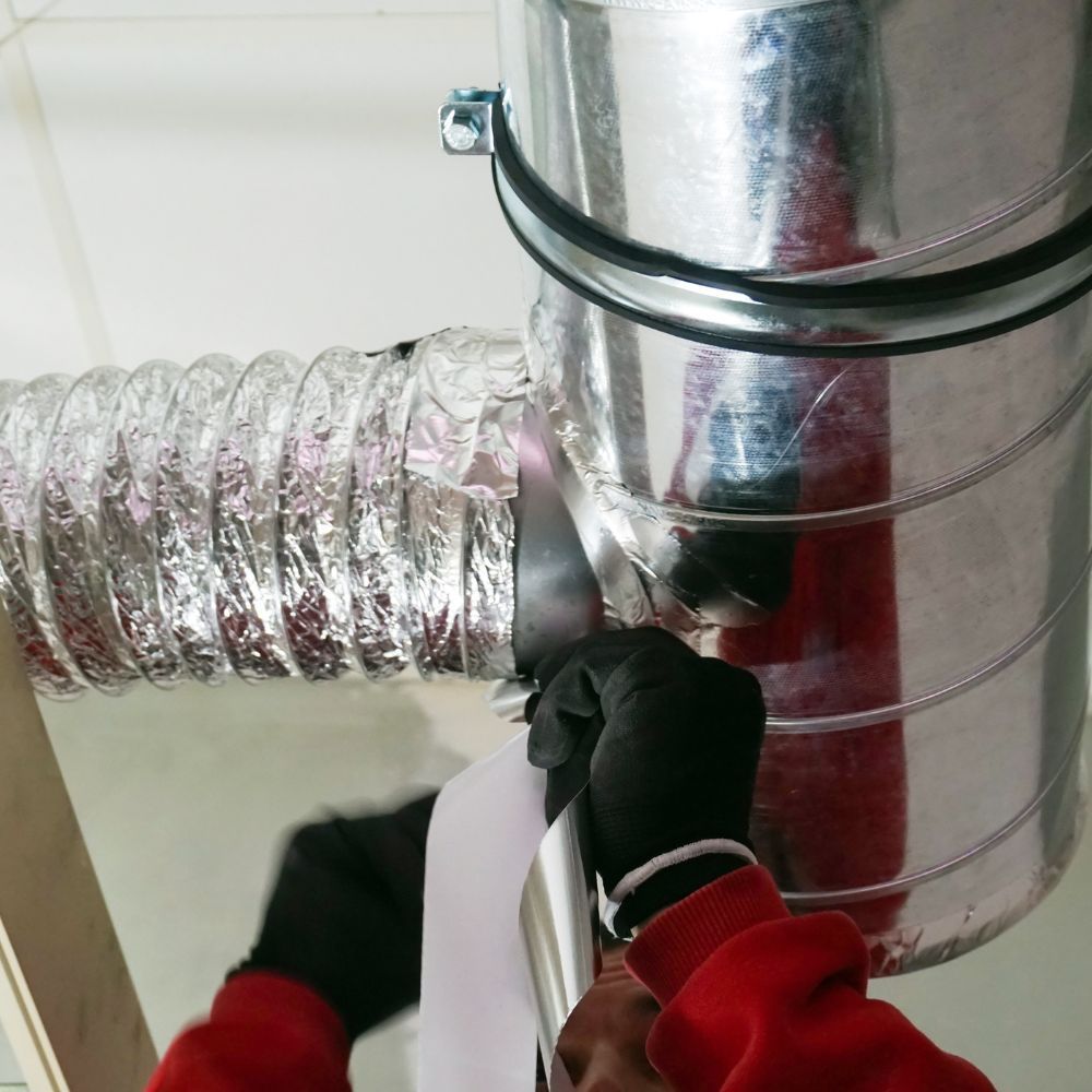 A person wearing black gloves is working on a metal pipe