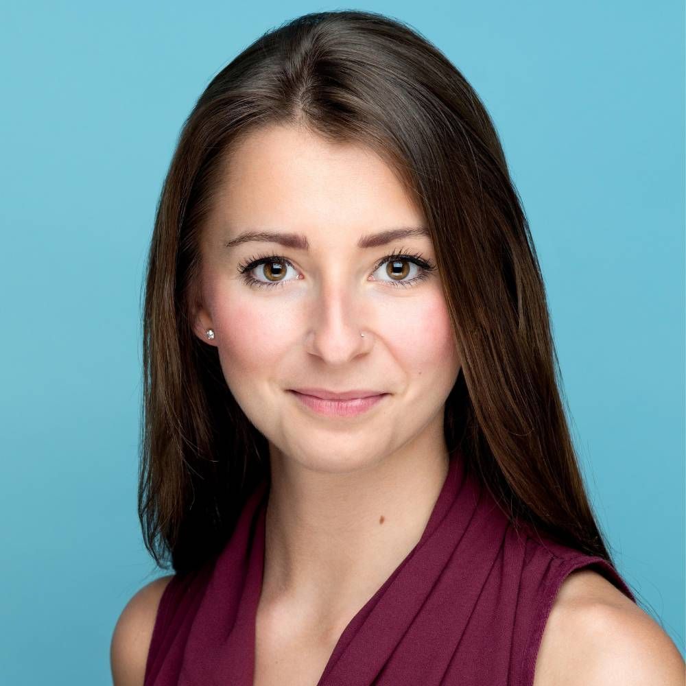 A woman in a purple dress is smiling for the camera.