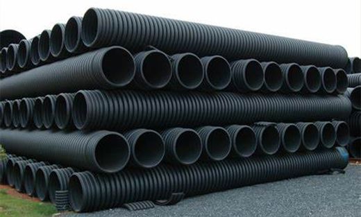 Stacks of large black plastic drainage pipes stored outdoors