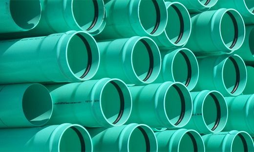 Stacked turquoise plastic pipes arranged in rows