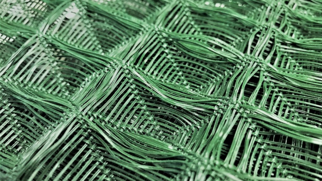 Green woven wire mesh stacked in overlapping layers, creating a textured pattern.