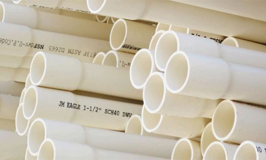 Stacked white PVC pipes with printed labels on a shelf