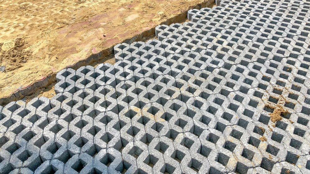 Gray interlocking pavers installed beside a dirt edge, forming a textured ground surface