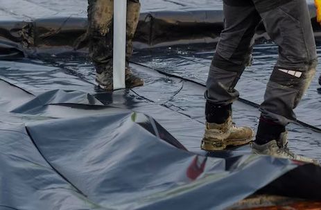 Worker walking on black rooftop underlayment during roof installation