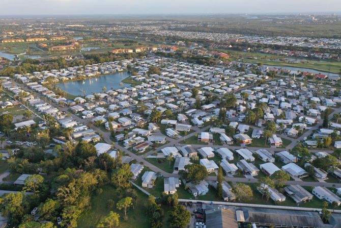 Aerial view of a suburban neighborhood with rows of white-roofed houses, trees, and streets at dusk