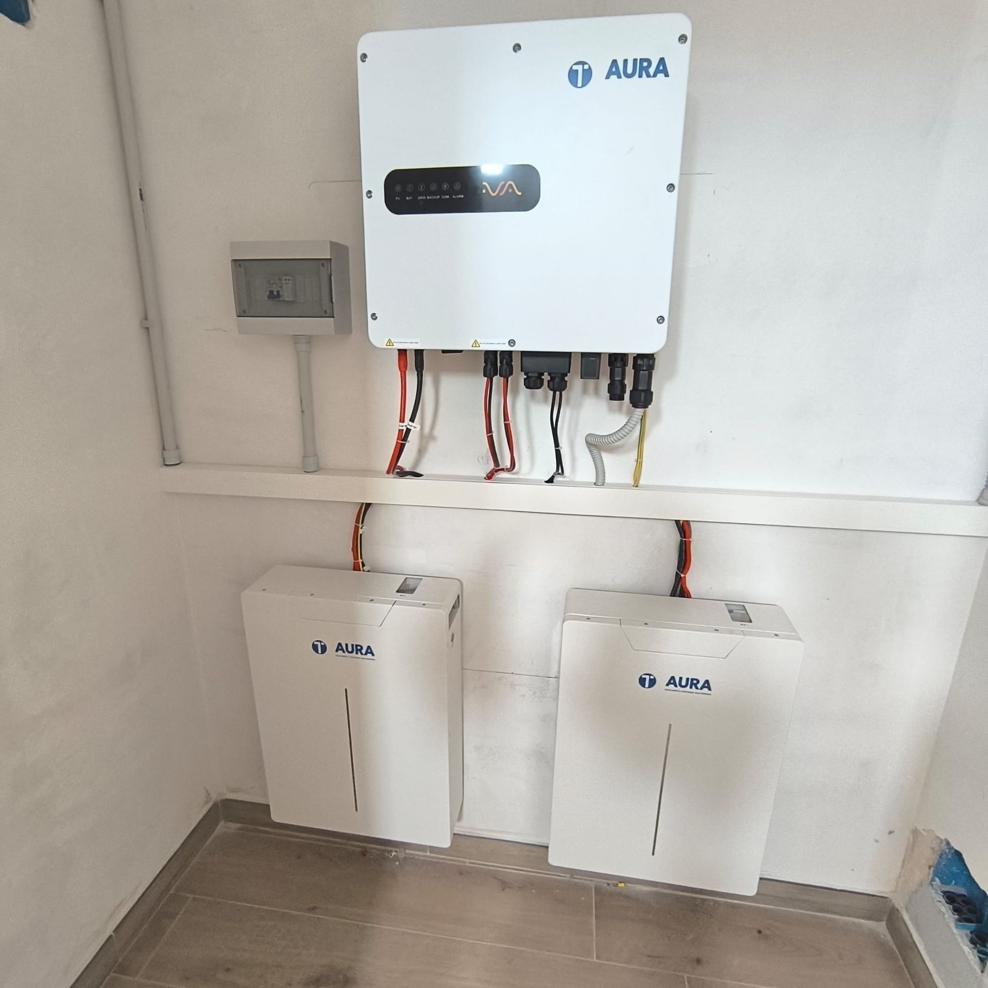 Inverter solare a parete e due unità di accumulo a batteria in un locale tecnico.