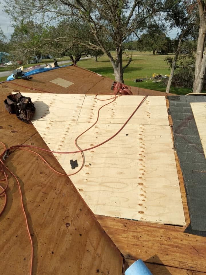 Roofing materials and tools laid out on a wooden roof deck under construction outdoors.