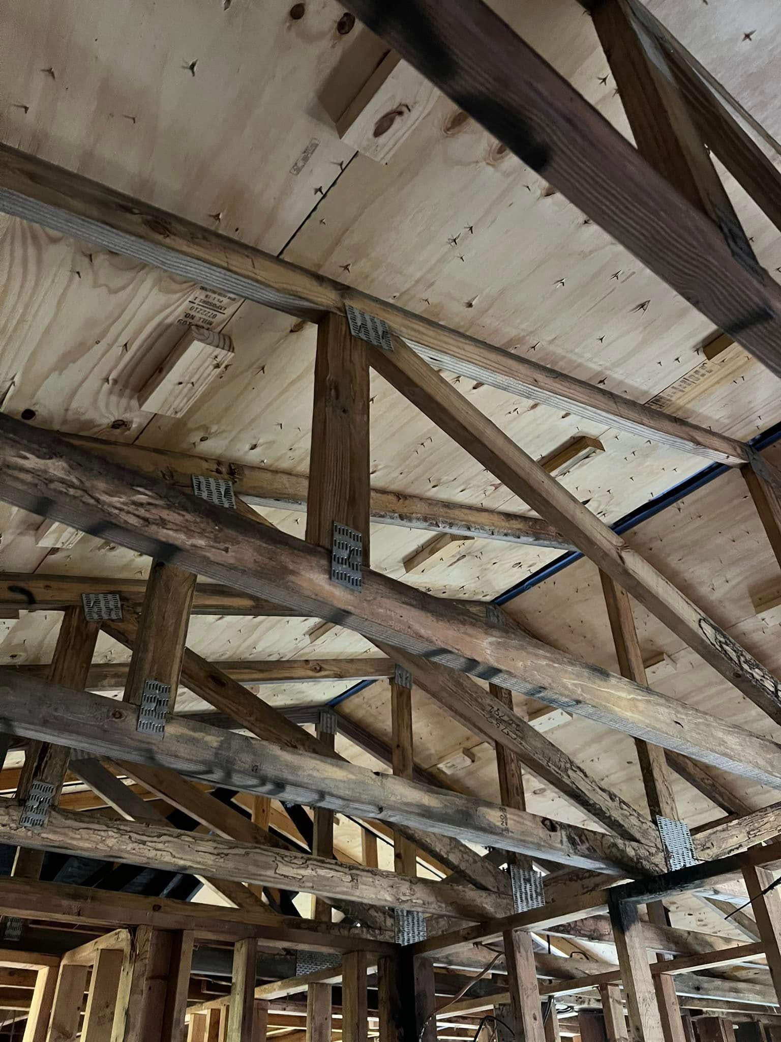 Interior of an unfinished wooden roof with exposed beams and plywood sheathing