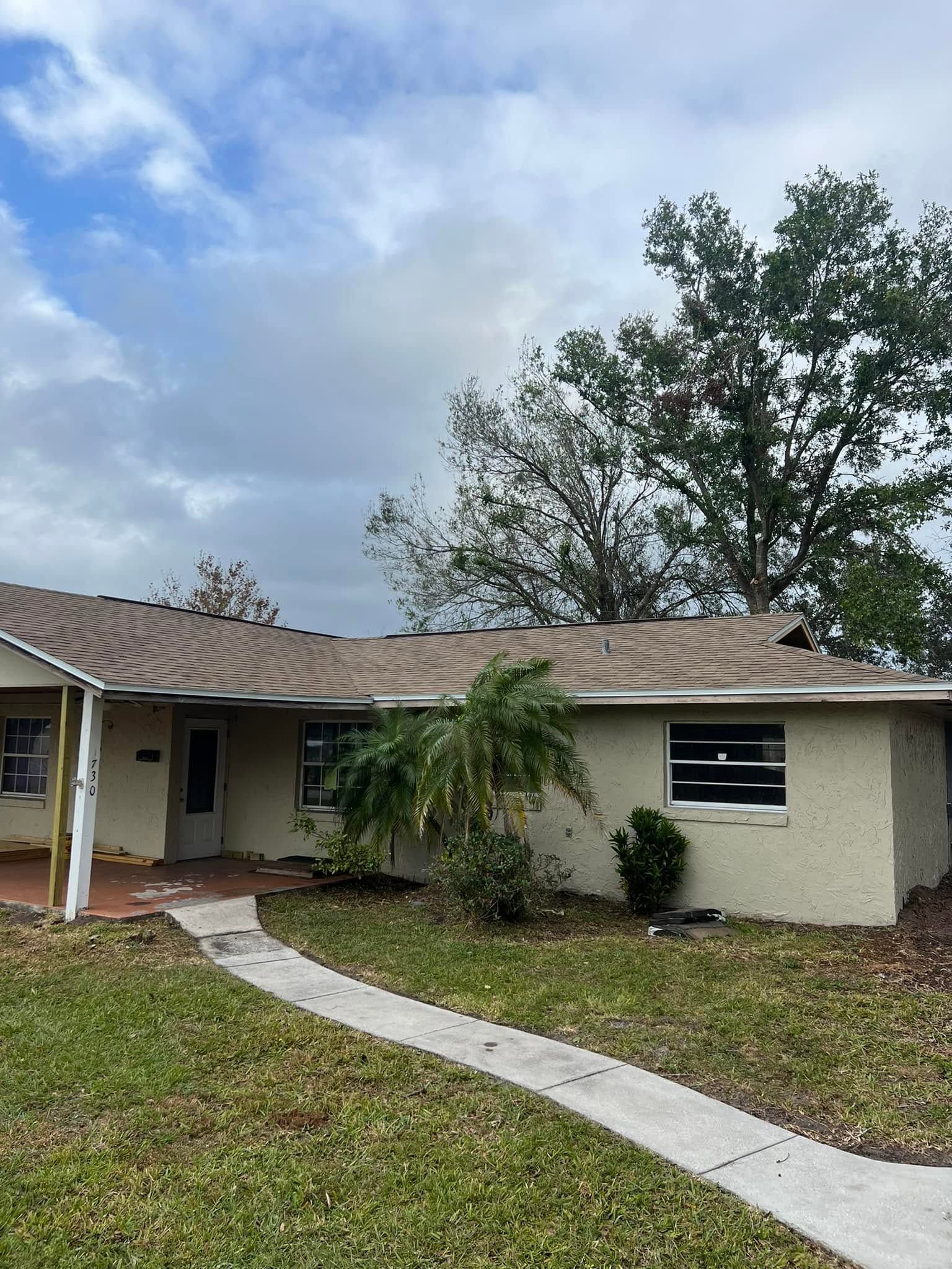 Single-story beige house with a curved walkway and overcast sky