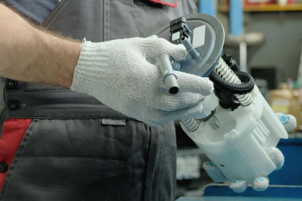 A Man Wearing Gloves Is Holding A Fuel Pump In His Hands — Reef Diesel Injection In Moranbah, QLD