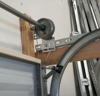 an image of a sectional garage door mechanism showing the torsion pole, cable drum and curved track. 