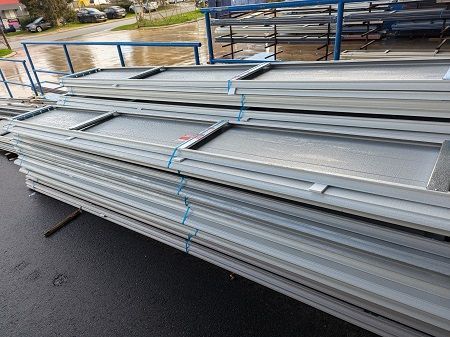 A stack of metal garage door panels  sitting on top of each other on the ground.