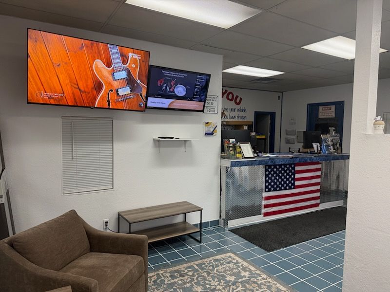 Waiting room with brown chair, wall TVs, and a front desk draped with an American flag.