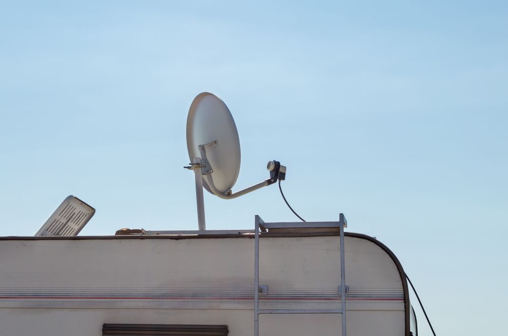 Satellite Dish Mounted on a White Camper Roof Against a Blue Sky — Total Caravan Repairs in Taree, NSW