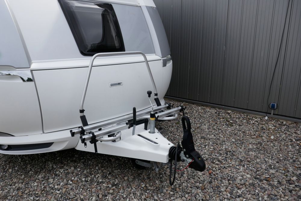 a White Caravan With a Silver Bike Rack Mounted on the Front — Total Caravan Repairs in Taree, NSW