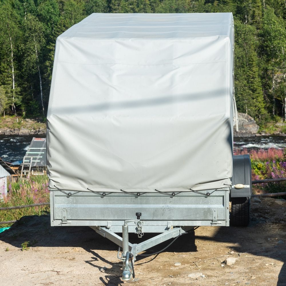 Gray Trailer With a Canvas Cover Parked Outdoors — Total Caravan Repairs in Nabiac, NSW