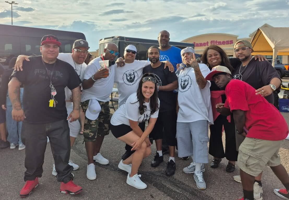Group of people posing together outdoors, smiling and dressed in black, white, and red clothing.