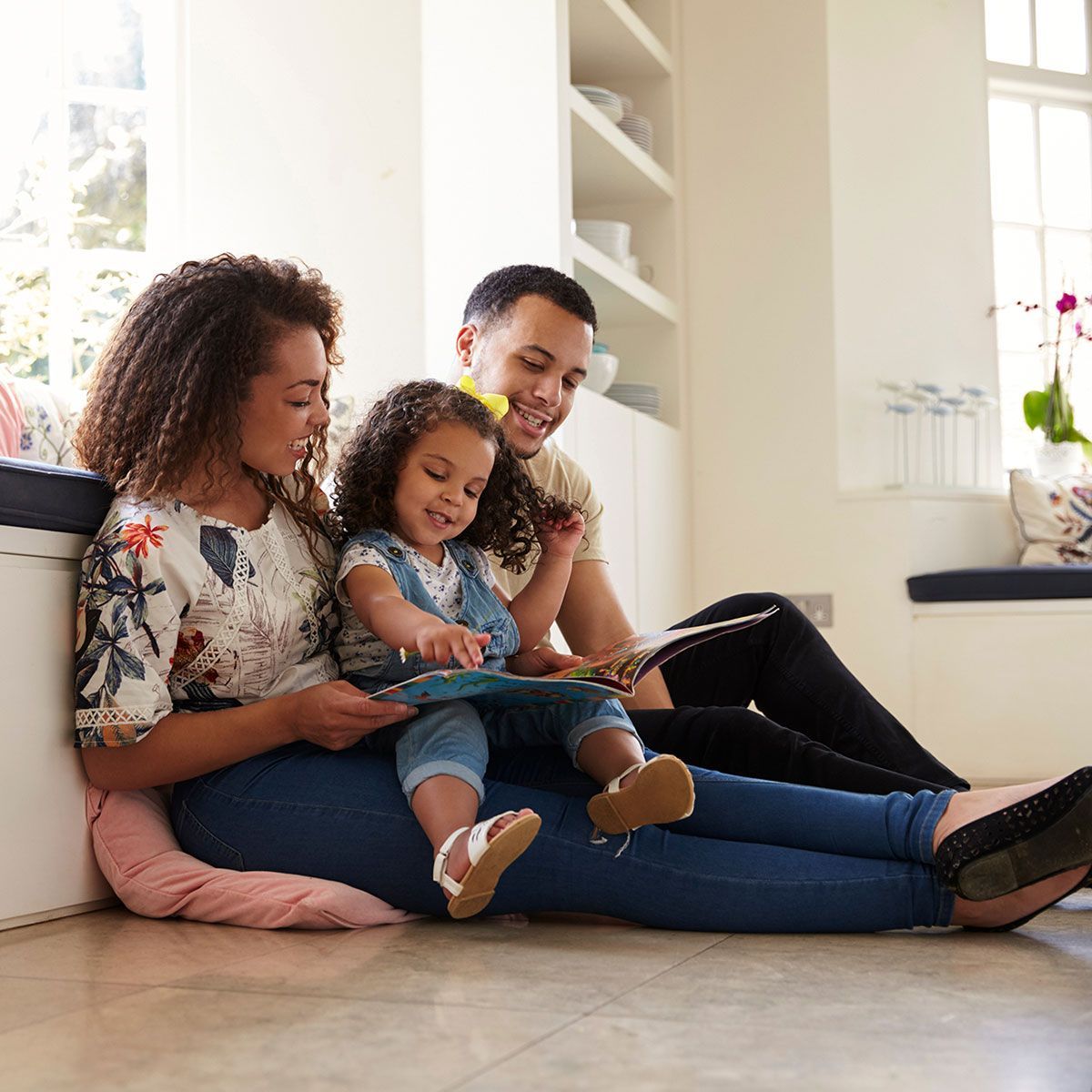 Parents and their daughter sitting on the floor reading book
