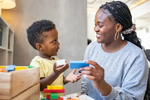 A teacher is sitting on the floor talking to a group of children.