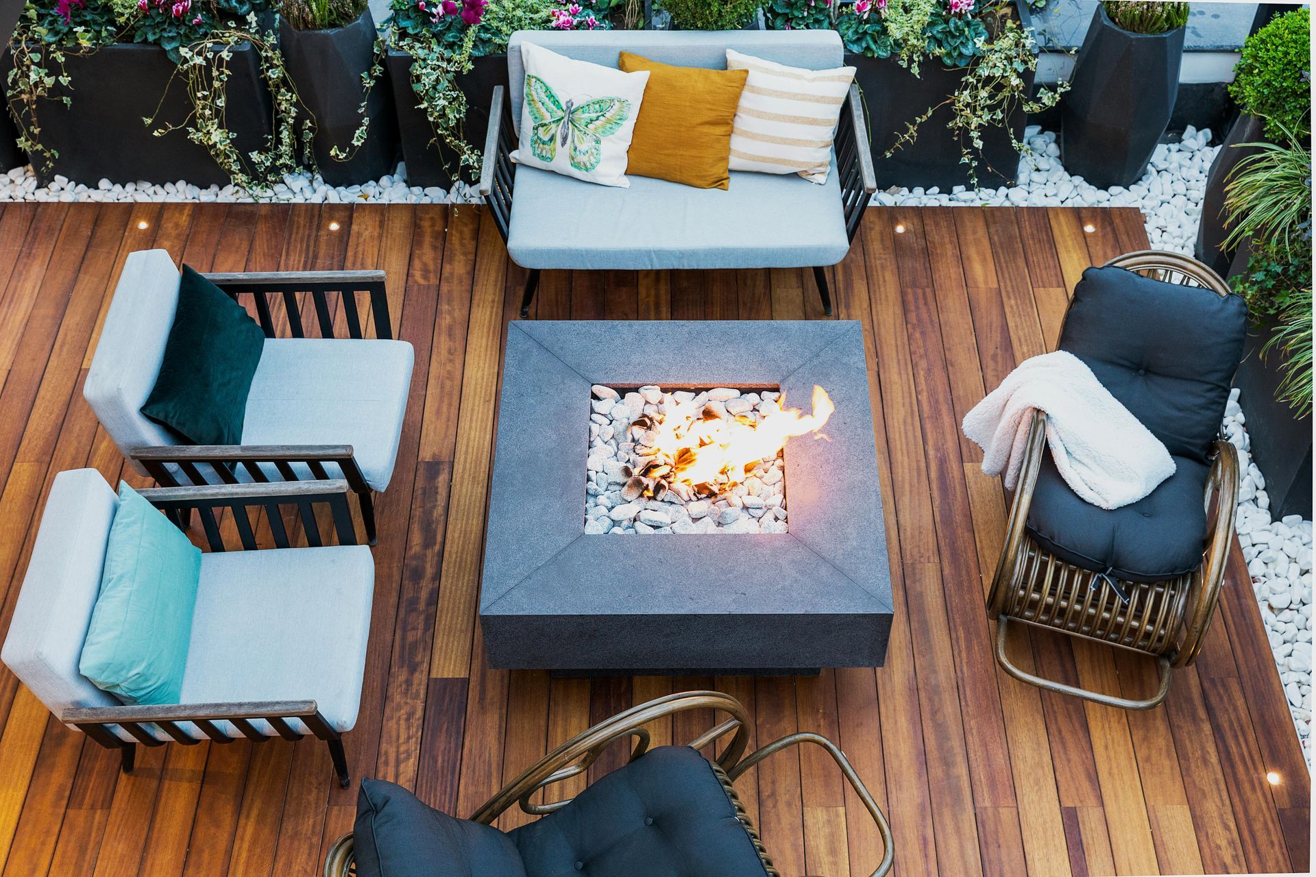 Outdoor seating area with fire pit, wooden deck, and potted plants.