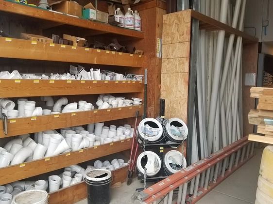 Shelves of white PVC pipes and fittings in a hardware store aisle