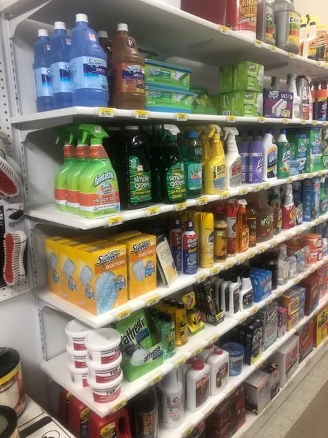 Store aisle stocked with cleaning products, soaps, and detergents on white shelves.