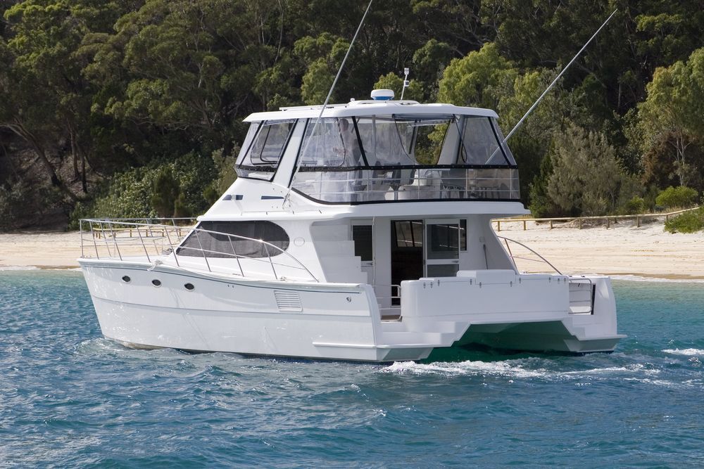 White Motor Yacht on Blue Water Near a Lush Green Shoreline — McCabbin Marine In Bowen, QLD