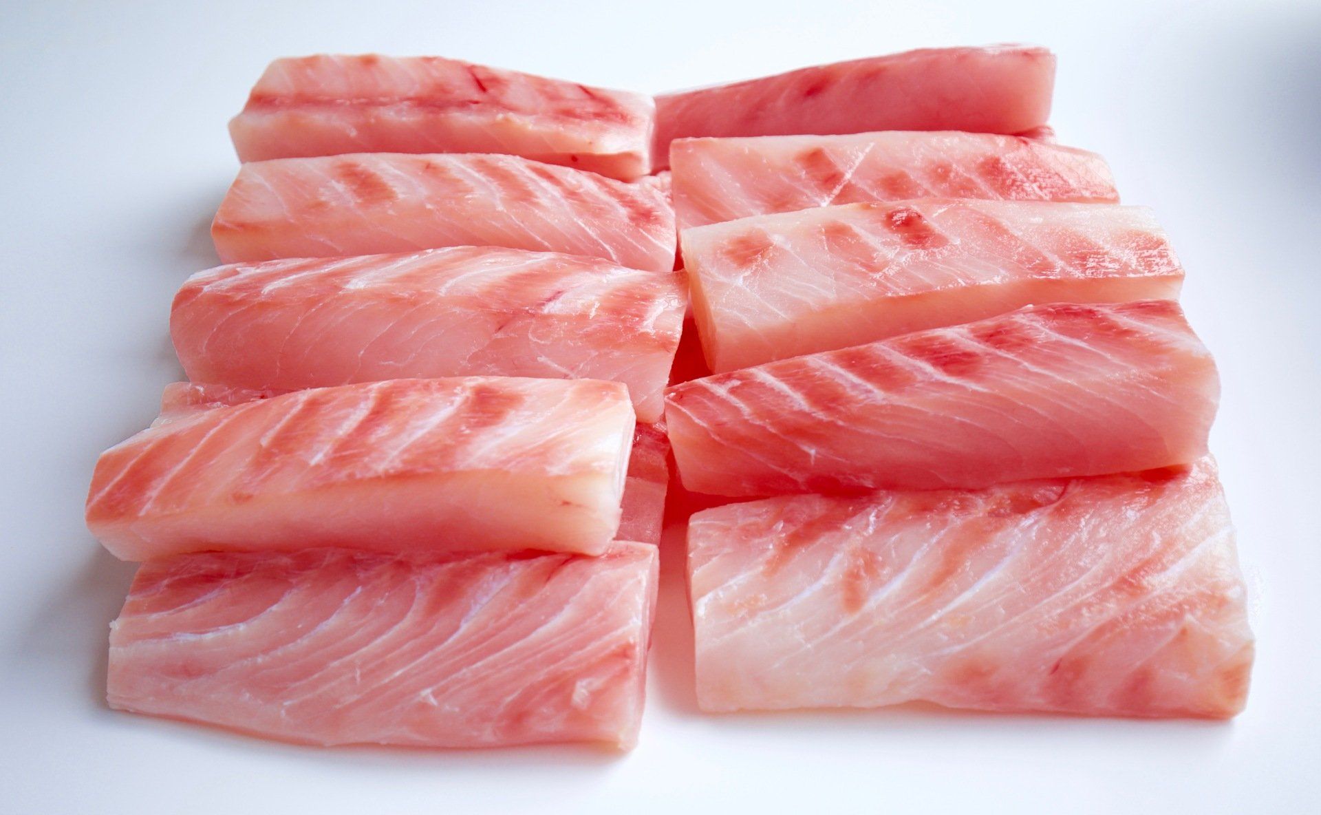 Ten rectangular slices of raw, pinkish-white fish arranged in two columns against a plain white background.