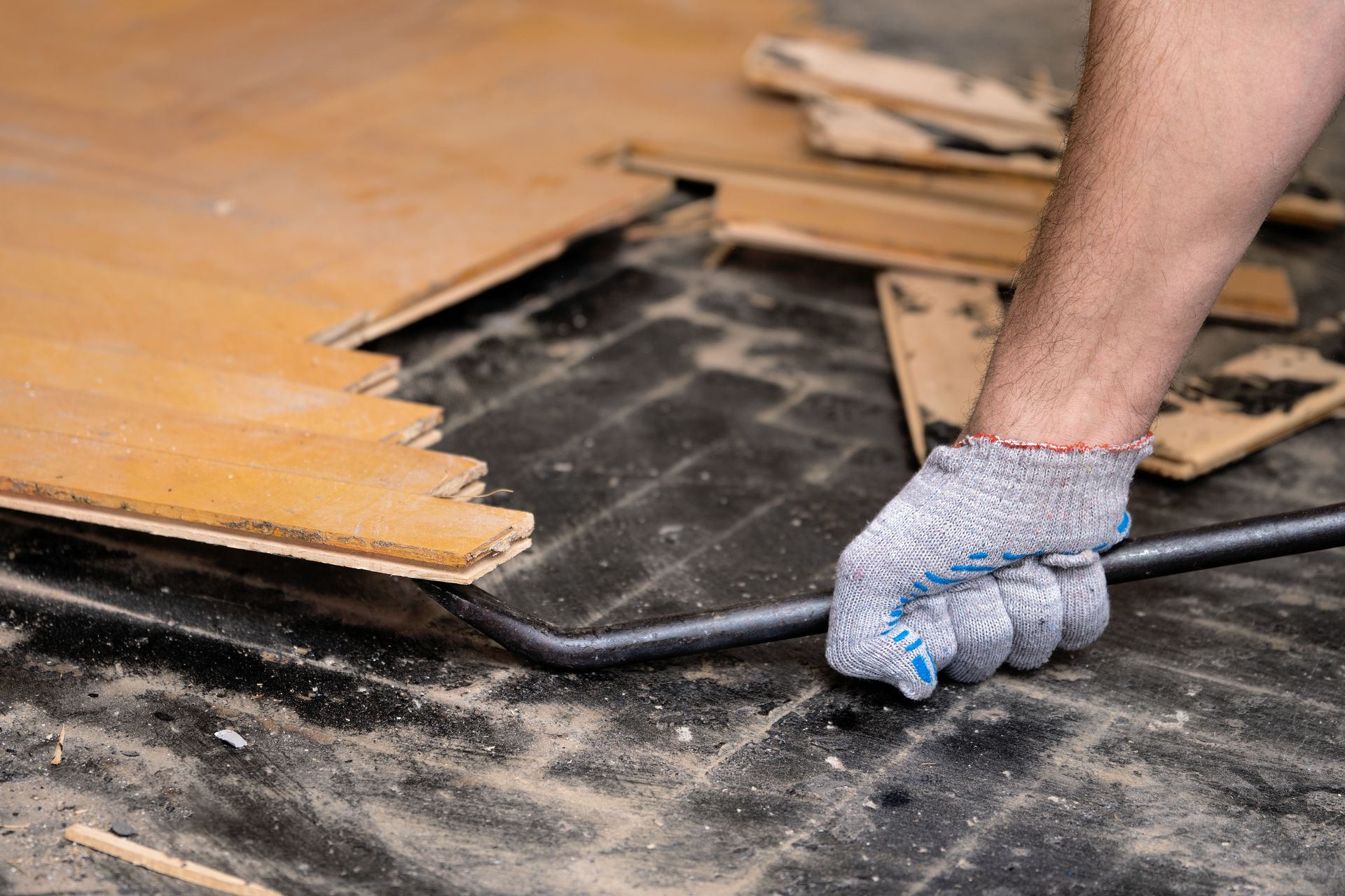 Une personne utilise un pied de levier pour retirer un parquet endommagé.