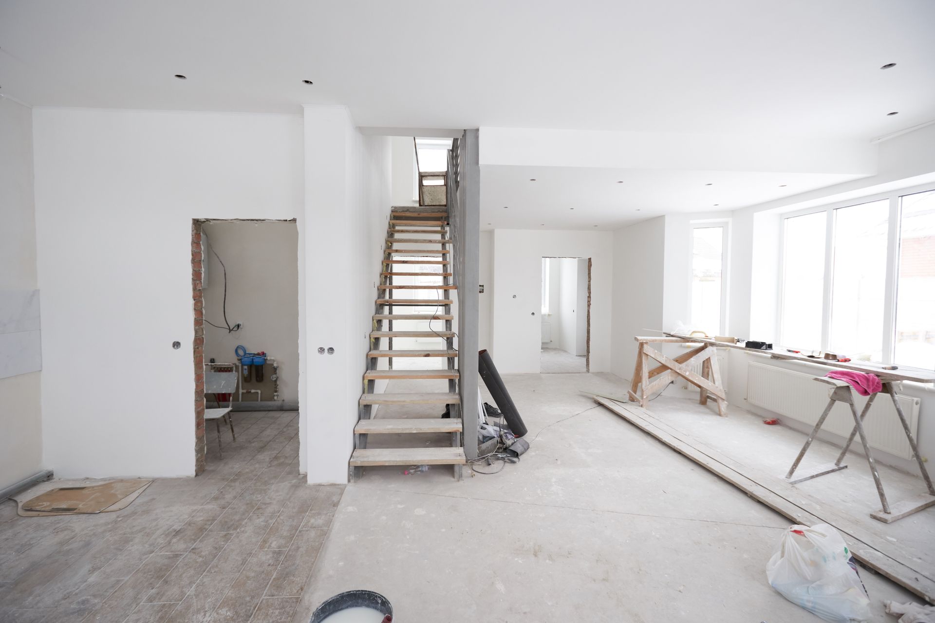 Intérieur d'un bâtiment en rénovation, avec des murs inachevés, un escalier et des matériaux de construction.