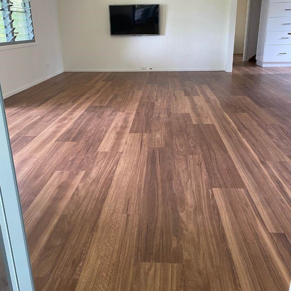 A Living Room With a Wooden Floor and a Flat Screen Tv on the Wall — John Chisholm Flooring in Cairns, QLD