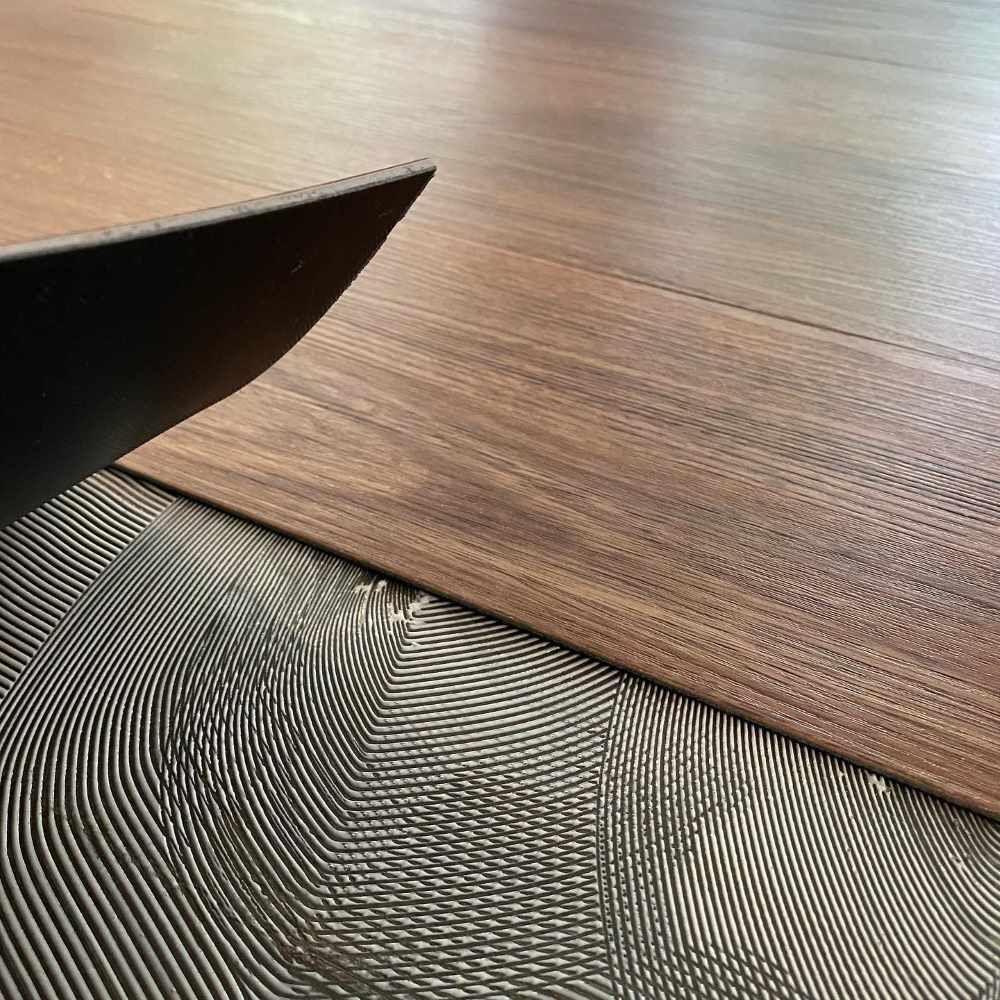 A Man is Installing Vinyl Flooring — John Chisholm Flooring in Cairns, QLD