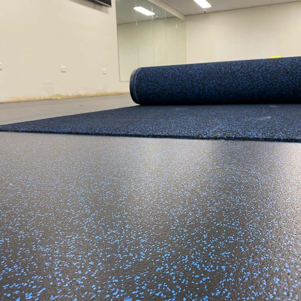 A Roll of Blue Rubber Flooring is Sitting on Top of a Black Floor — John Chisholm Flooring in Cairns, QLD