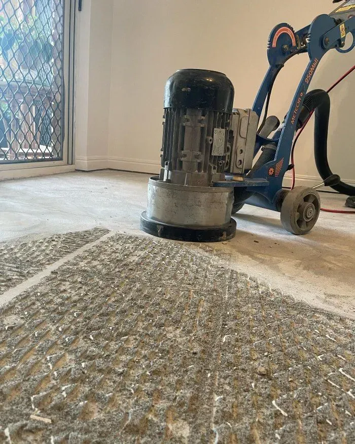 A Grinder is Sitting on a Concrete Floor in a Room — John Chisholm Flooring in Cairns, QLD