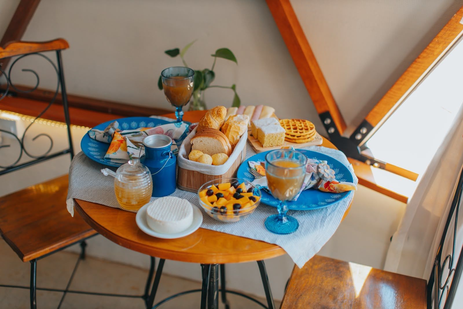 Chá e doces sobre uma toalha de mesa azul em um aconchegante recanto para refeições no sótão.