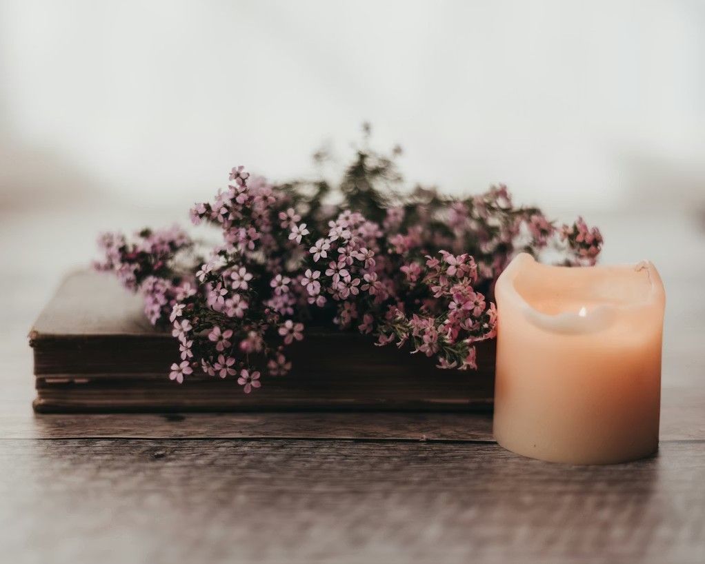 Soft candle and pink flowers beside a book representing funeral and cremation services in Franklin Park, IL