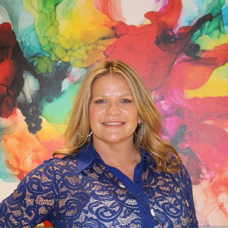 A woman in a scrub top is smiling for the camera.