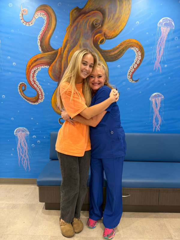 Two people hugging in front of a mural of an octopus and jellyfish underwater scene
