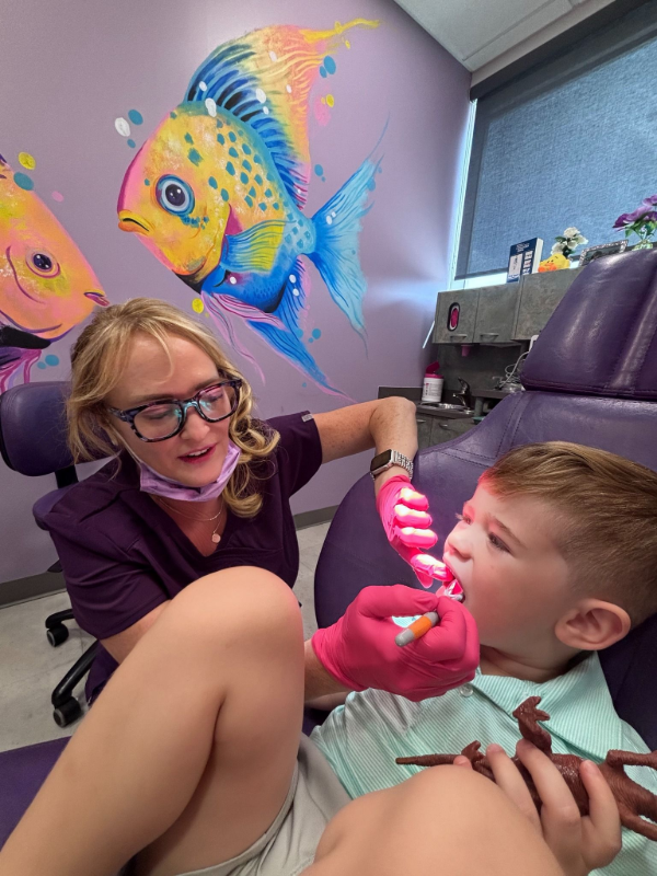 Dentist working on a child’s teeth in a colorful dental exam room