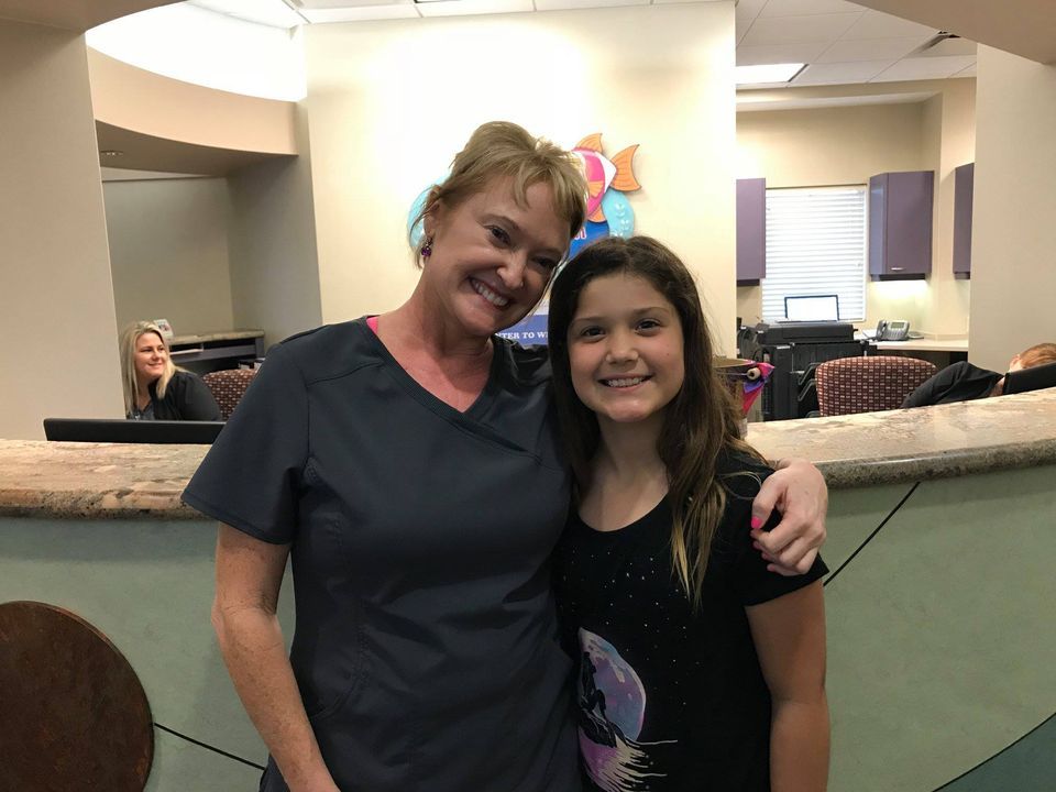 A woman and a girl are posing for a picture in a dental office.